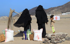 Yemeni women wait for a ride with their food aid