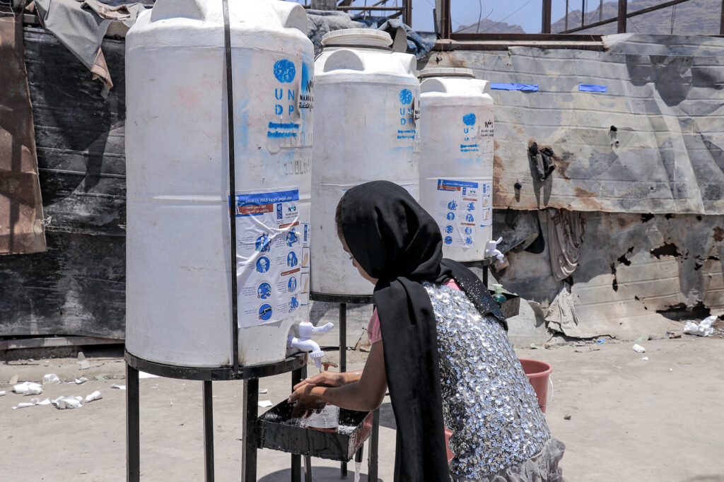 A girl washes her hands at communal taps at an IDP camp