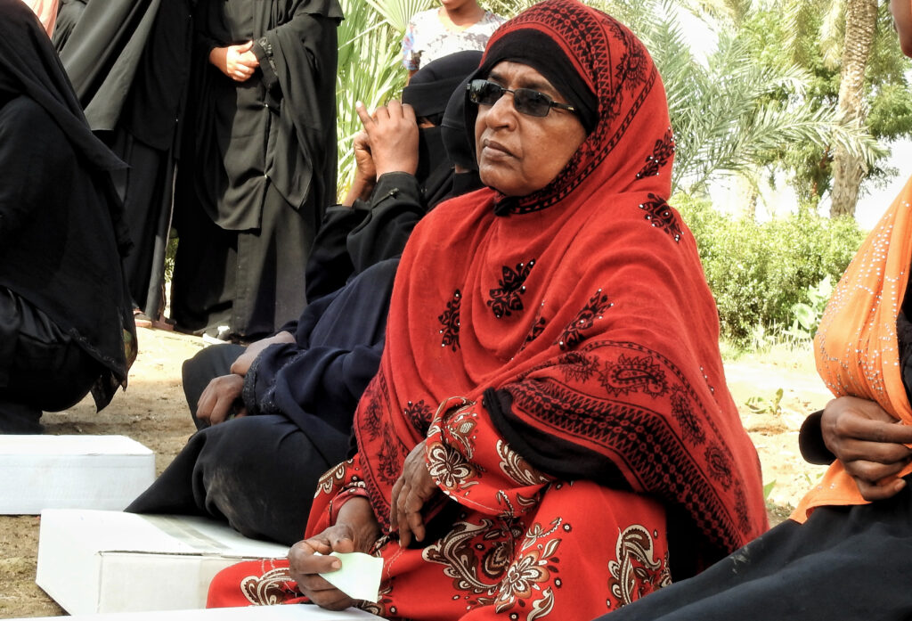 Women sit with boxes of dates in a food queue at an IDP camp